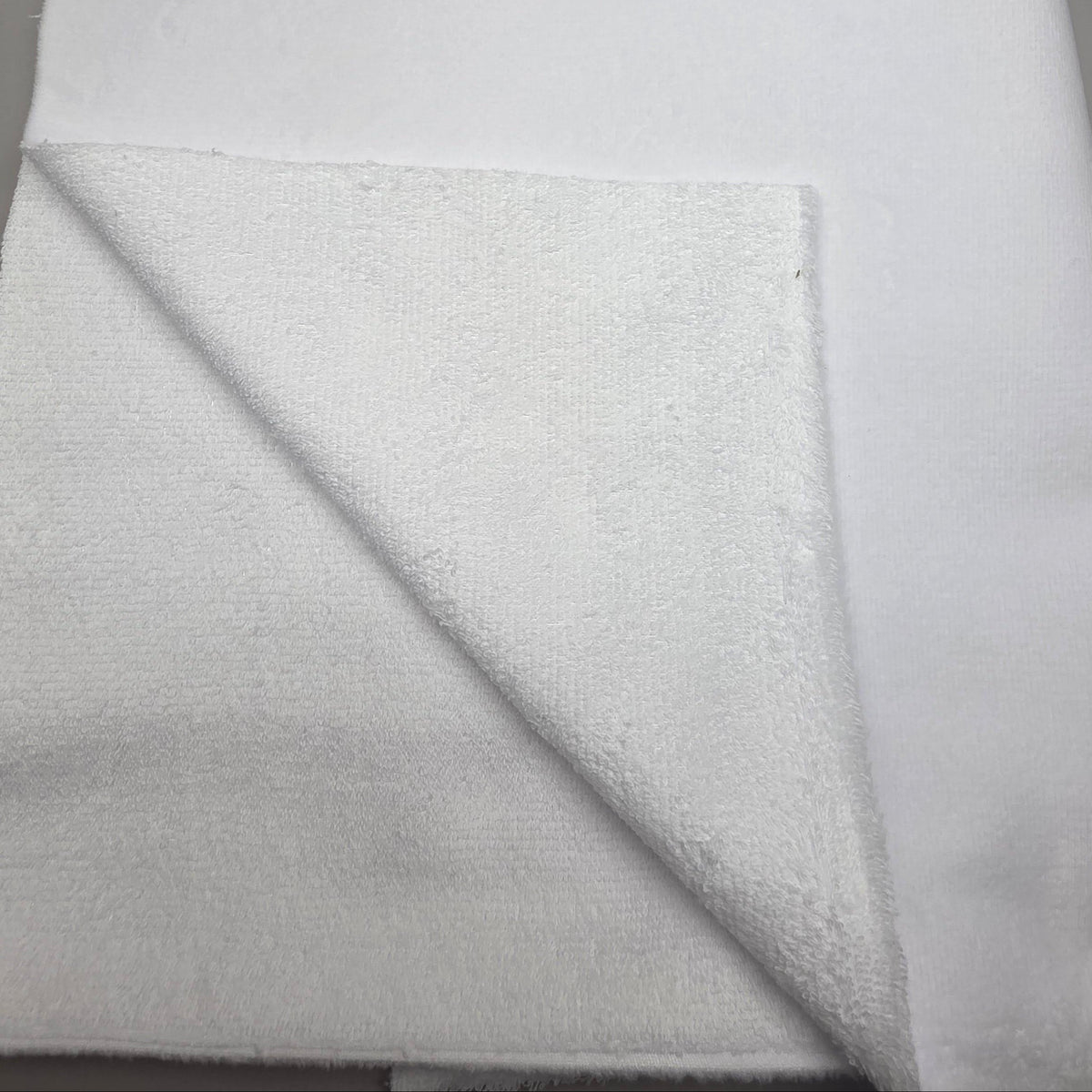 A folded white terry cloth towel or fabric piece shown against a plain gray background.